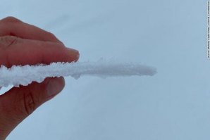 pesquisador segura um pedaço de gelo que se formou após a chuva no cume da Gronelândia