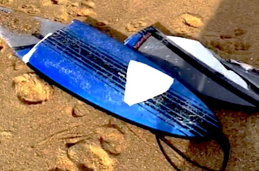 Mota de agua parte a prancha de um surfista à remada na Nazaré
